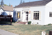 Picture of the Empire Branch Library on G Street. There is a sign over the door and a large sign in the grass. The library had been a house so has a porch and steps leading to the door