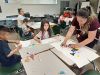 Parents and children working a a project at desks