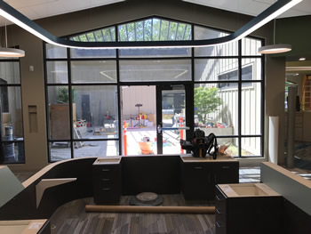 Double glass door with windows surrounding it on both sides and the top. The courtyard area can be seen through the glass. There is a cemented area with plants in round planters.